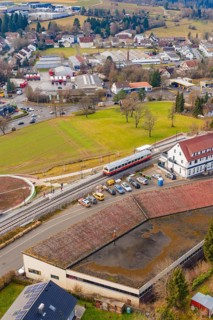 A train stops at a train station in a small town area with residential buildings, historic event,