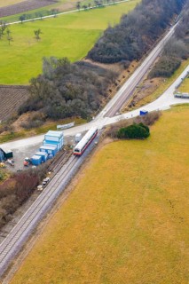 Train at a rural crossroads, surrounded by fields and some trees, northwestern perspective,