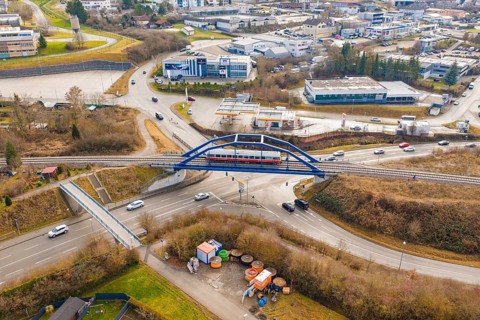A train crosses a busy road junction in the city on a bridge, historical event, first test drive