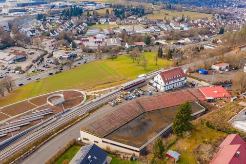 A train at a large train station, surrounded by residential buildings and roads, historic event,