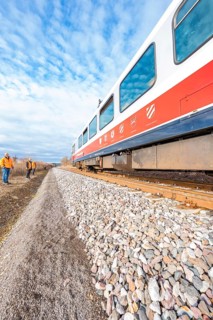 Perspective view of a moving train on rails under a blue sky with clouds, historical event, first
