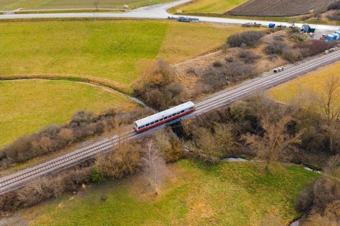 Train crosses a scenic bridge between winter fields and trees, historic event, first test run with