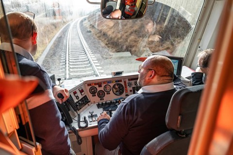 Team in the driver's cab of a train, looking at the railway tracks in front of them, historic