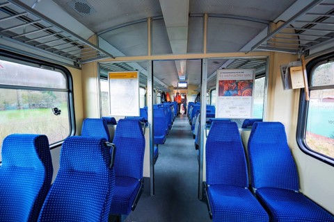Neatly arranged blue seats inside a train with lots of daylight, historic event, first test run