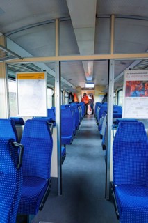 Interior of a train with blue seats and windows through which daylight enters, historic event,