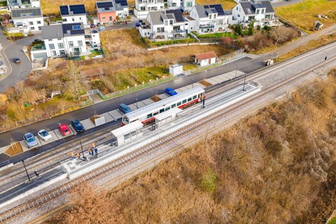 Small train stops at a railway stop within a residential development, historic event, first test