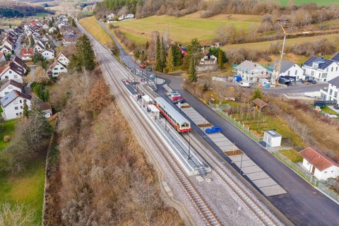 Railway station in rural area with train and rail, surrounded by houses and trees in an autumnal