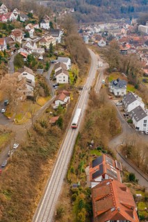 A train travels through a hilly urban landscape with numerous buildings, historical event, first
