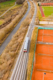 Railway tracks run next to tennis courts and a path in a wintry landscape, historic event, first