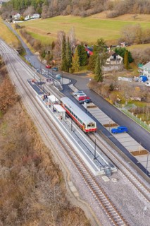Small train station in a rural area with train, rails and surrounding countryside in autumn colors,
