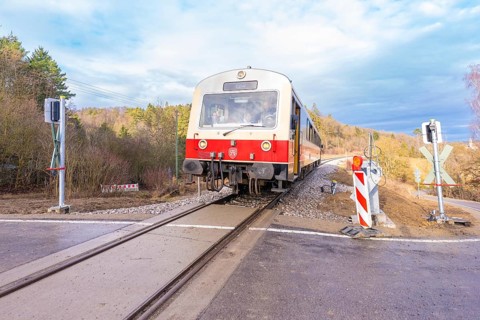 Train on a rail crossing, surrounded by trees, under a cloudy sky, historic event, first test run