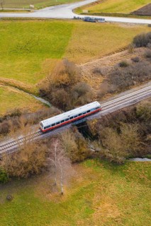 A train crosses a bridge over a river, surrounded by trees in a rural landscape, historic event,