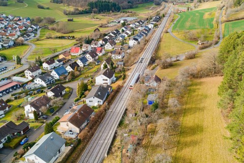 Railway tracks criss-cross a village backdrop with houses and green spaces, historic event, first