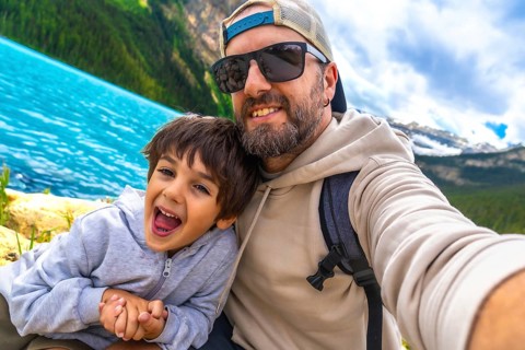 Happy father and son capturing a selfie by the turquoise waters of lake louise, surrounded by