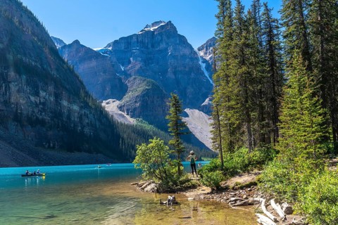 Tourists are canoeing on the turquoise, glacier fed moraine lake with its surrounding mountains and