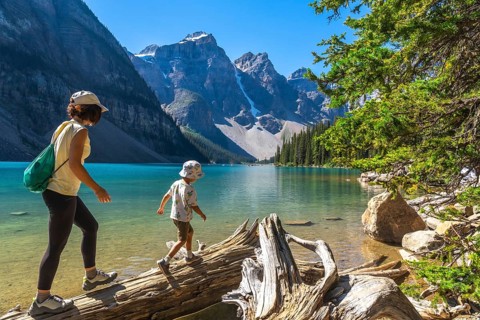 Mother and son enjoying a leisurely walk on a weathered log along the scenic shores of moraine