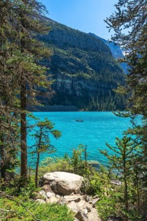 Tourists are canoeing on the turquoise, glacier fed moraine lake with the scenic valley of the ten
