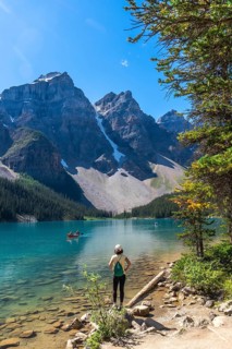 Female tourist standing on the shore of pristine turquoise moraine lake, admiring the majestic