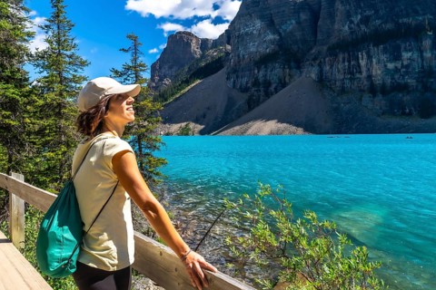 Female tourist admiring the turquoise waters of moraine lake, with the stunning valley of the ten