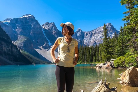 Female tourist standing at the shore of turquoise moraine lake enjoying the breathtaking view of