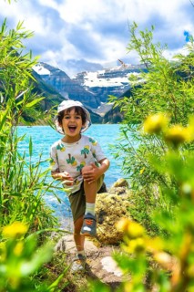 Young child having fun by the turquoise waters of lake louise with the majestic rocky mountains in