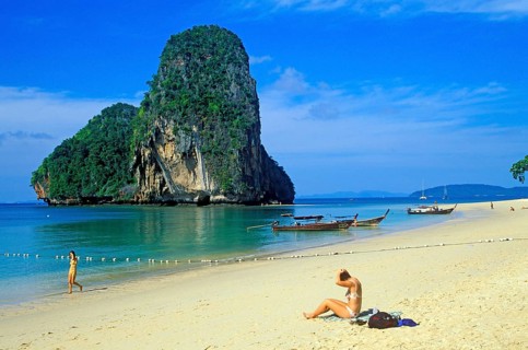 Rocks in the sea, people and longtail boats on Pranang Cave beach, two years in front of the