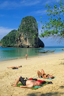 Rocks in the sea, people and longtail boats on Pranang Cave beach, two years in front of the
