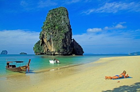 Rocks in the sea, people and longtail boat on Pranang Cave beach, two years in front of the