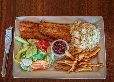 Plate of fried fish fillet with salad and french fries on wooden table, Top view of delicious fried