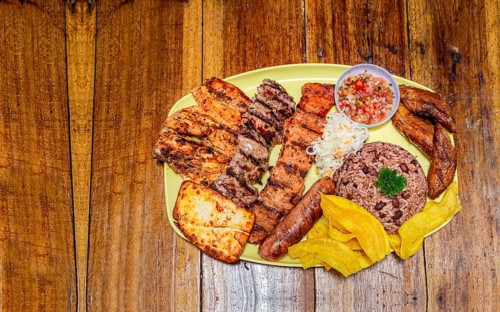 Varieties of grilled meats with rice, fried cheese and tomato salad, plate with assorted types of