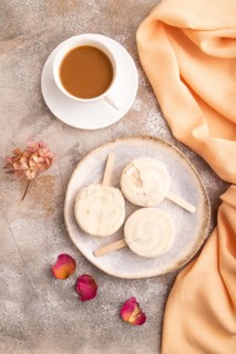 ?hocolate Ice cream in white glaze, cup of coffee, on brown concrete background and orange textile,