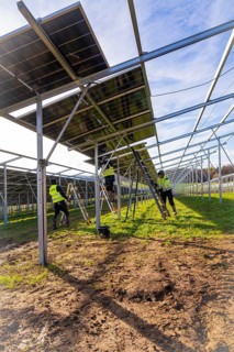Workers install solar panels in a meadow, energy revolution, construction of PV open space,