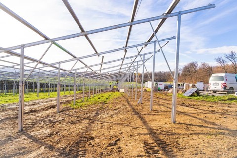 Unfinished solar system in open area with vehicles and building materials, energy transition,