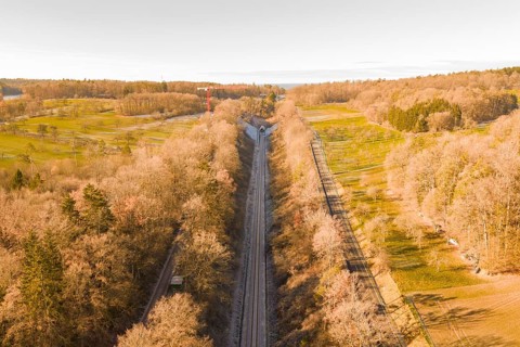 Train route from above, flanked by autumnal forests, running through nature, construction of the