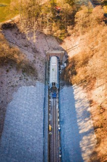 Railway line under a bridge through an autumnal forest, taken from the air, construction of the