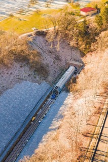 A Train Emerges from a Tunnel Surrounded by Forested Hills in a Wintry Setting, Construction of the