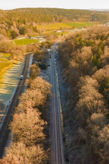 Railway line between trees and a country road in an autumn landscape, construction of the Hermann