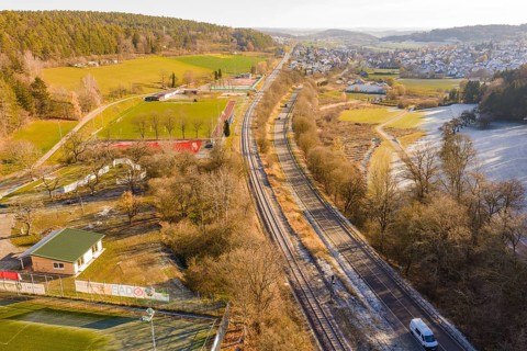 Aerial view of a railway running parallel to fields and a village nestled in a wintry landscape,