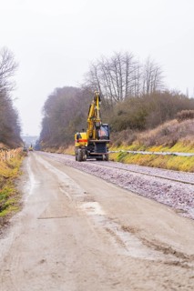 Railway tracks and an excavator on a construction site in a cloudy landscape, construction of the