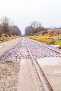 Railway tracks run in perspective through a cloudy landscape, construction of the Hermann Hesse