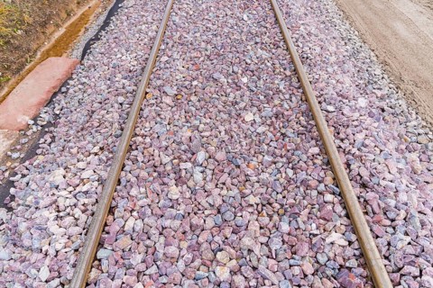 Close-up of railroad tracks covered with grey and purple gravel, construction of the Hermann Hesse