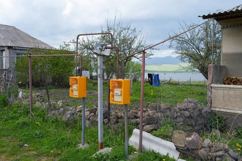 Two yellow gas meters next to a fence overlooking a lake and rural area, Sameba, Kvemo Kartli