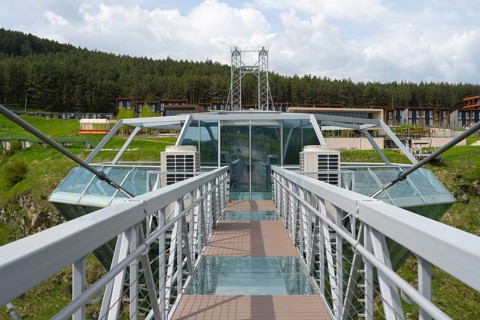 View from a modern glass bridge surrounded by forest and buildings, Diamond Glass Bridge, world's