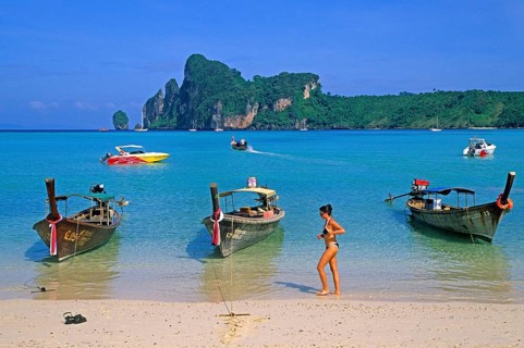 Young woman, longtail boats on the beach of Ko Phi Phi Don, two years in front of the tsunami,