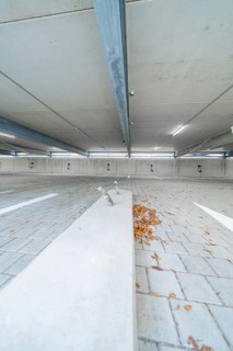 Empty parking lot with concrete floor, scattered leaves and parking space markings, parking garage