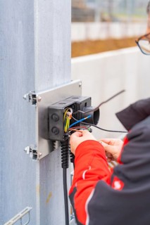 Person working on an electrical installation, cables are being connected, parking garage