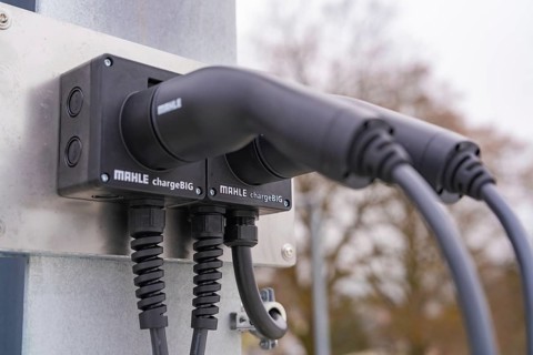 Two electronic chargers with cables on a metal bracket, parking garage construction with charging