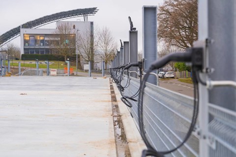 Row of charging stations with a modern building in the background, parking garage construction with