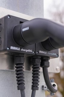 Close-up of charging stations with two black cables, mounted on metal, parking garage construction