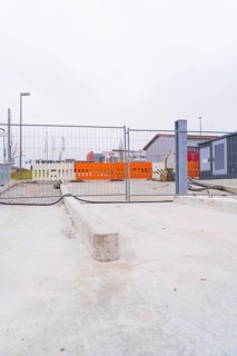 View of a cordoned off construction site with concrete floors and fences, parking garage